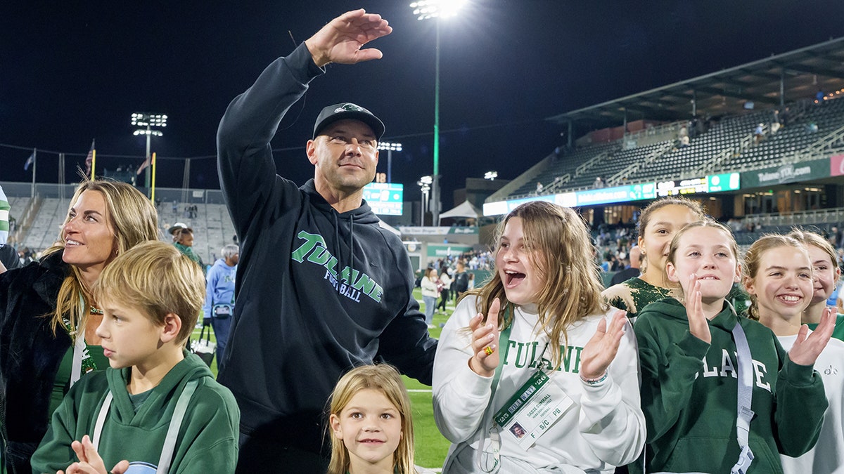 Tulane head coach Jon Sumrall celebrating with family and players on football field