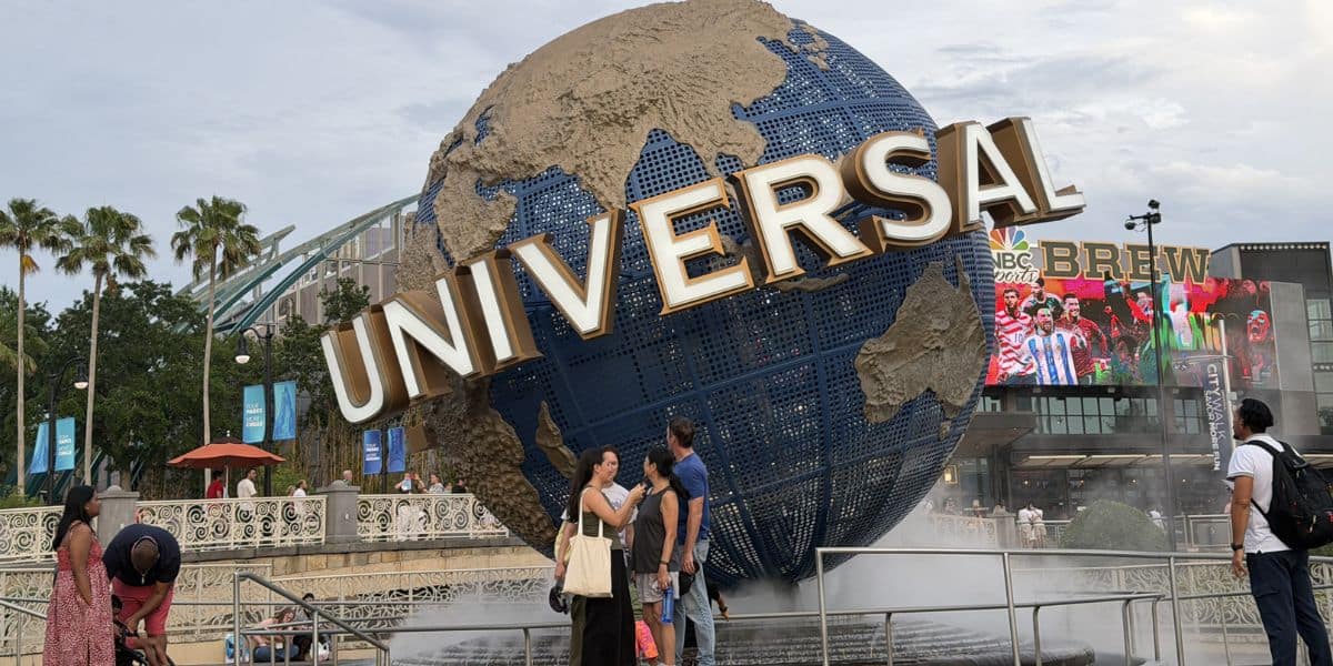 The iconic Universal globe spins at the entrance to Universal Studios, with excited guests gathering for a day of adventure.