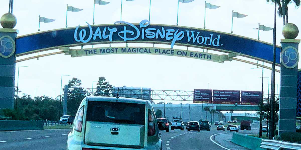 Cars driving under the entrance archway of the Walt Disney World Resort