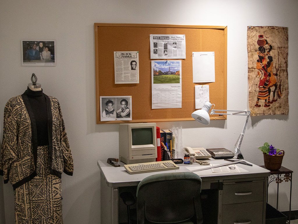 A vintage desktop computer, telephone and office desk, evoking a newsroom or editorial workspace from the 1980s and 1990s.