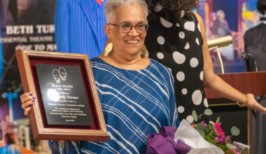Beth Turner, founder and publisher of Black Masks magazine, holds a commemorative plaque and bouquet during a ceremony recognizing her decades of contributions to Black arts, culture and journalism. The recognition was presented as part of the “Black Masks” exhibition at Florida A&M University’s Foster-Tanner Fine Arts Gallery, which celebrates the magazine’s 40-year legacy. (Photo courtesy of FAMU Essential Theatre.)