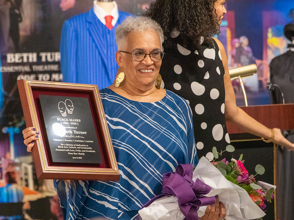 Beth Turner, founder and publisher of Black Masks magazine, holds a commemorative plaque and bouquet during a ceremony recognizing her decades of contributions to Black arts, culture and journalism. The recognition was presented as part of the “Black Masks” exhibition at Florida A&M University’s Foster-Tanner Fine Arts Gallery, which celebrates the magazine’s 40-year legacy. (Photo courtesy of FAMU Essential Theatre.)