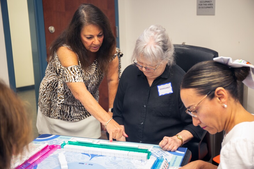 Judy Serrapica teaches two players how to play the American version of Mahjong