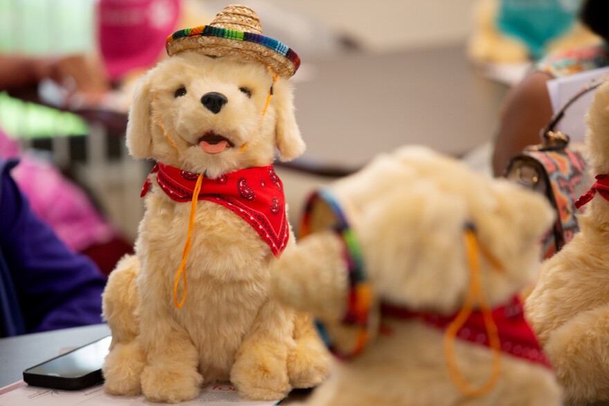 A close up of a small yellow electronic dog with a red bandana and sombreo.