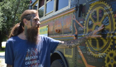 Cory Richez points Tuesday to the side of the Suicide Awareness Bus, where people have written the names of their loved ones who died by suicide. Any glitter on the bus is where ashes were painted onto the vehicle.