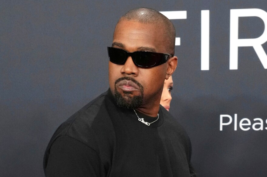 Black man with sunglasses and goatee wearing a black t-shirt and looking seriously to the left
