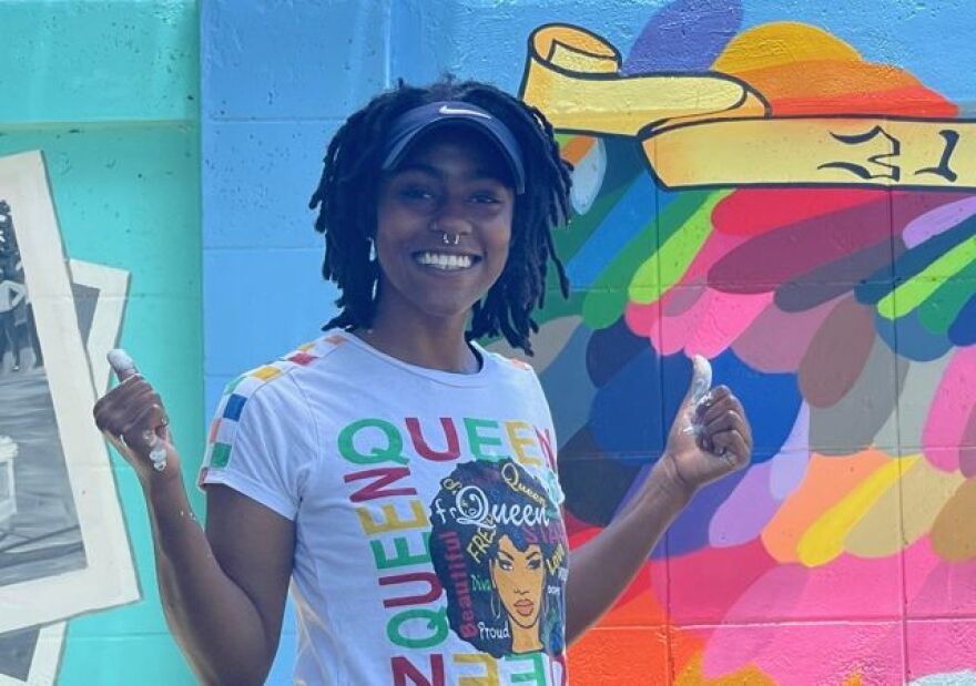 Dunbar resident enjoys one of the Buck's Backyard mural panels outside historic McCollum Hall.
