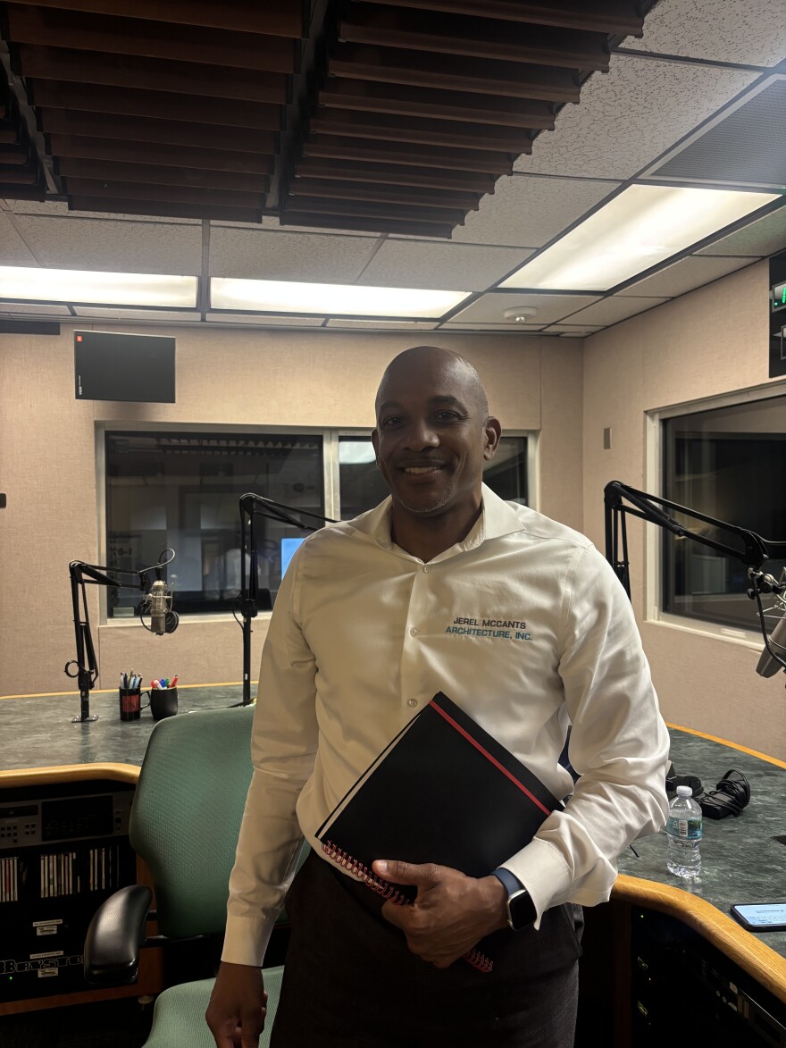 African American man with white shite stands in studio
