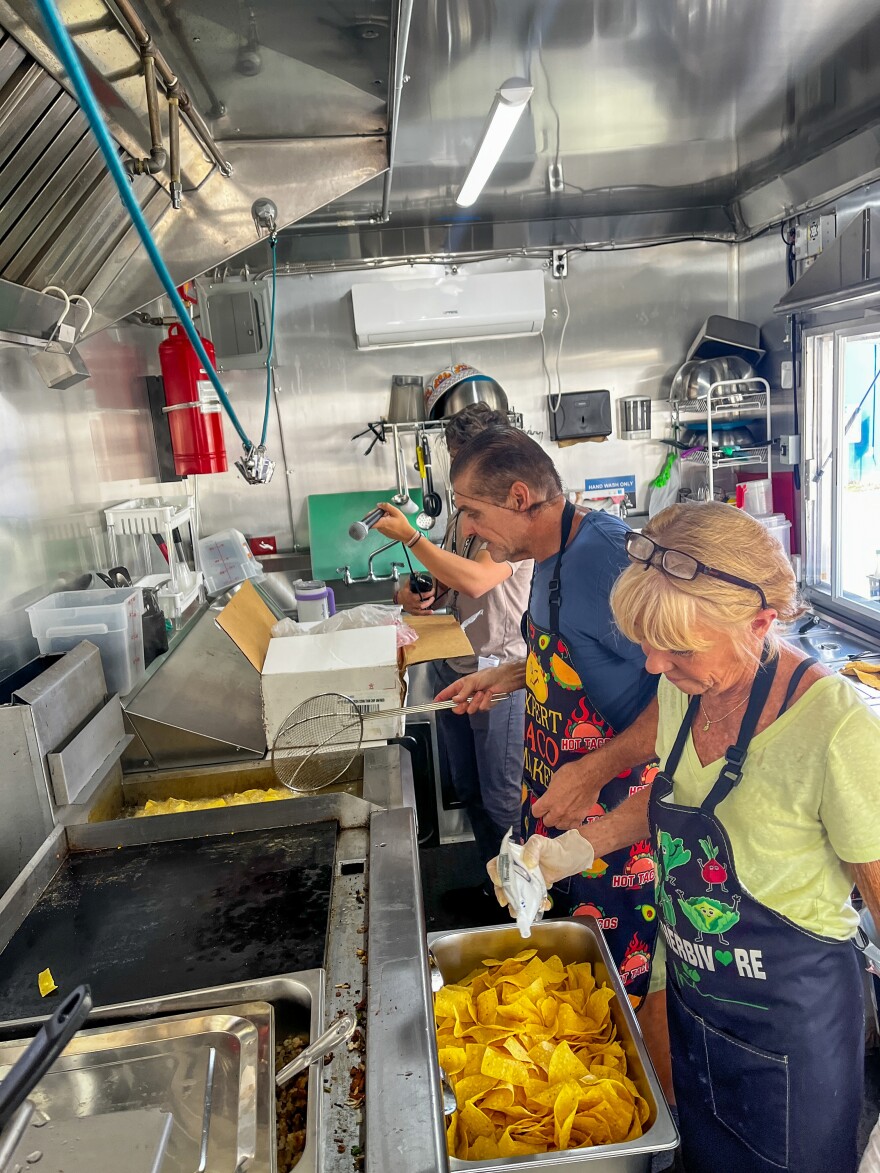 Man and woman frying chips, cooking inside a food truck
