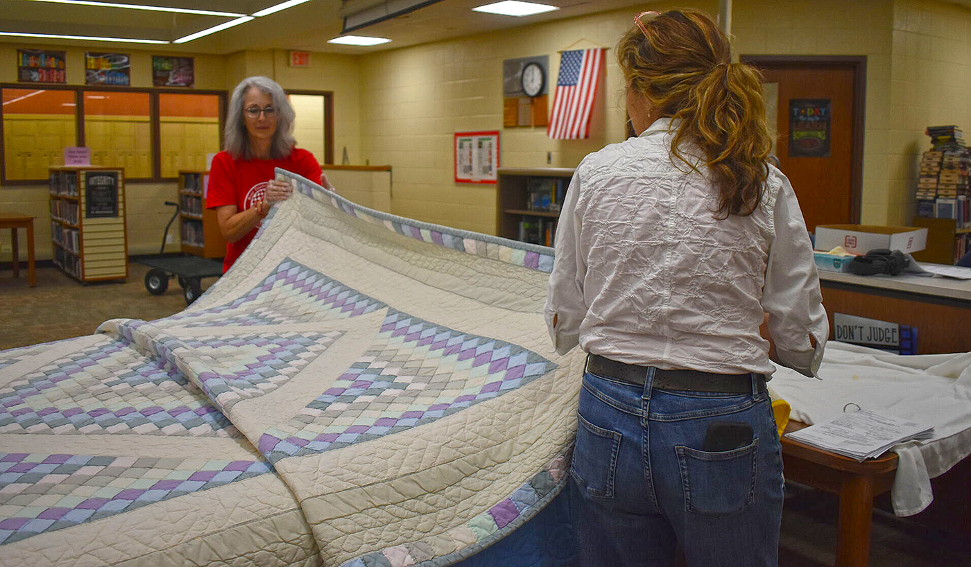 River Country Quilt Guild member Theresa Sauer (left) and volunteer Kathy Korte display a quilt during the River Country Quilt Show's bed turning. Organizers are accepting entries for quilts to display during this year's show at Jacksonville High School.