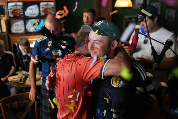Scotland soccer fans with bagpipes embrace amid confetti after playing together at the Ball and Chain music bar before the Tartan Army marches to a Miami Marlins against the Texas Rangers baseball game in Miami, Monday, June 22, 2026. (AP Photo/Rebecca Blackwell)