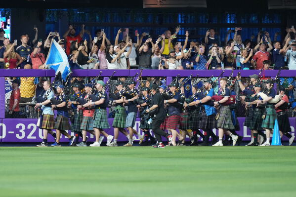 A bagpipe band marches in the outfield as Scotland soccer fans with the Tartan Army attend a baseball game between the Miami Marlins and the Texas Rangers, Monday, June 22, 2026, in Miami. (AP Photo/Lynne Sladky)