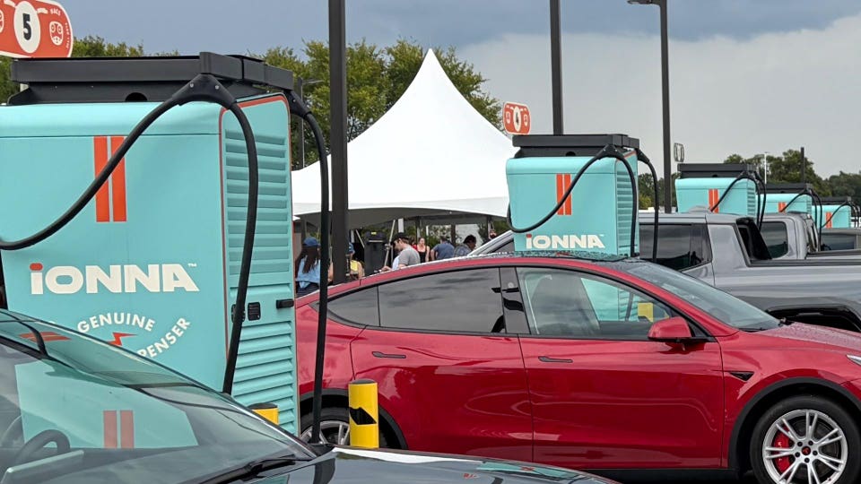 red Tesla parked next to teal ev charging stations