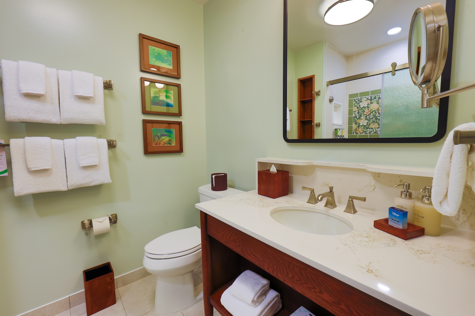 Mint Bathroom with a Double sink Vanity Large Mirror White Towels on Metal Racks and Tropical framed Art on the Wall