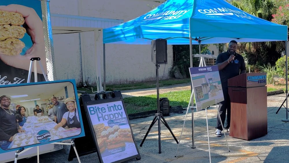 Arble Baking Co. co-founder Alonza Anderson stands under a tent talking about the new credit union office and sandwich bakery.