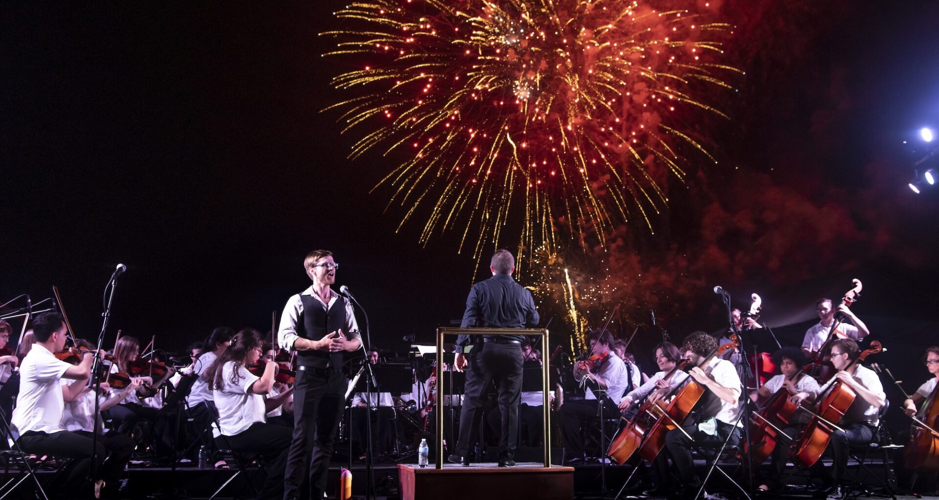 Photo of an orchestra performing in Miami Beach in front of Fire works