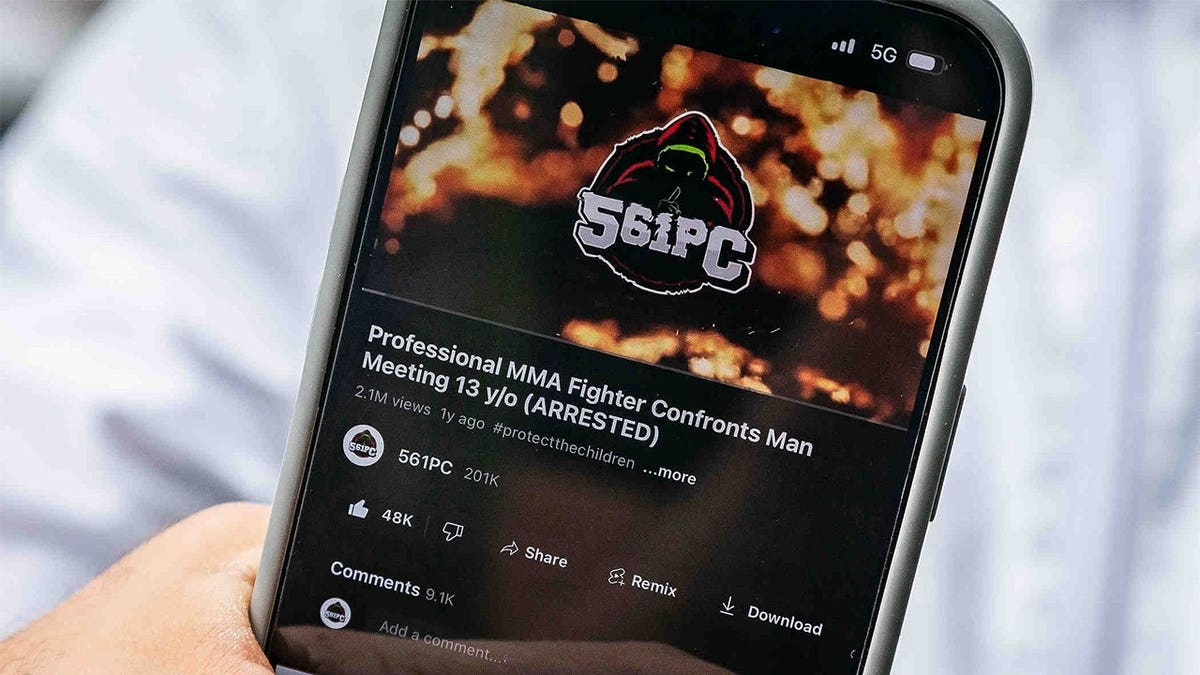Dustin Lampros holds phone to show 561 Predator Catchers