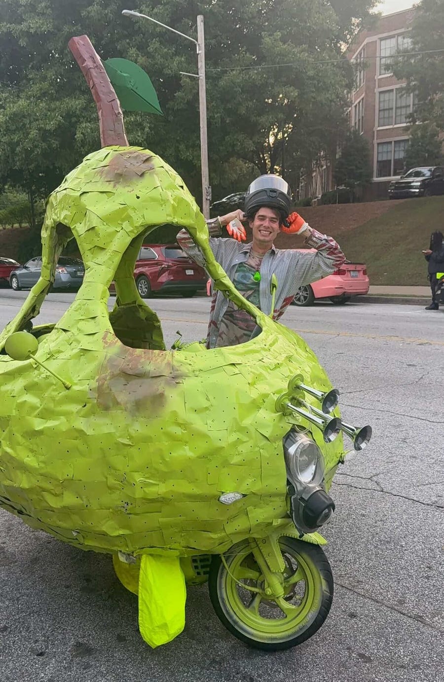 a custom vehicle shaped like a pear with a person posing beside it a custom vehicle shaped like a pear with a person posing beside it