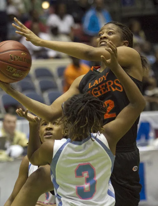 Dunbar High School's Kiara Desamours (12) goes up for a basket over Ribault High School's Sierra Shepherd (1), left, and Tierra Shepherd (3) during their FHSAA Girls Basketball 4A Championship Final game at the Lakeland Center Thursday. Dunbar won the game 50-41. February 23, 2012.