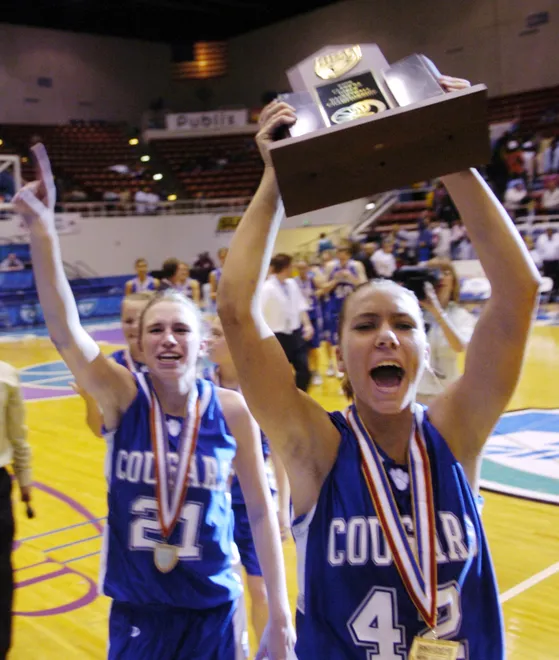 Barron Collier's Kasey Will (42) and Courtney Jacob takes the state championship trophy to the fans in the stands after they were presented with it after defeating Winter Haven 43-36 in Lakeland on Friday, Feb. 24, 2006.
