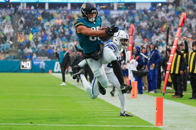 Jacksonville Jaguars tight end Brenton Strange (85) leaps for a touchdown as Indianapolis Colts cornerback Mekhi Blackmon (29) defends but is called back on a penalty during the fourth quarter of an NFL football game at EverBank Stadium, Sunday, Dec. 7, 2025, in Jacksonville, Fla. The Jaguars defeated the Colts 36-19. [Corey Perrine/Florida Times-Union]
