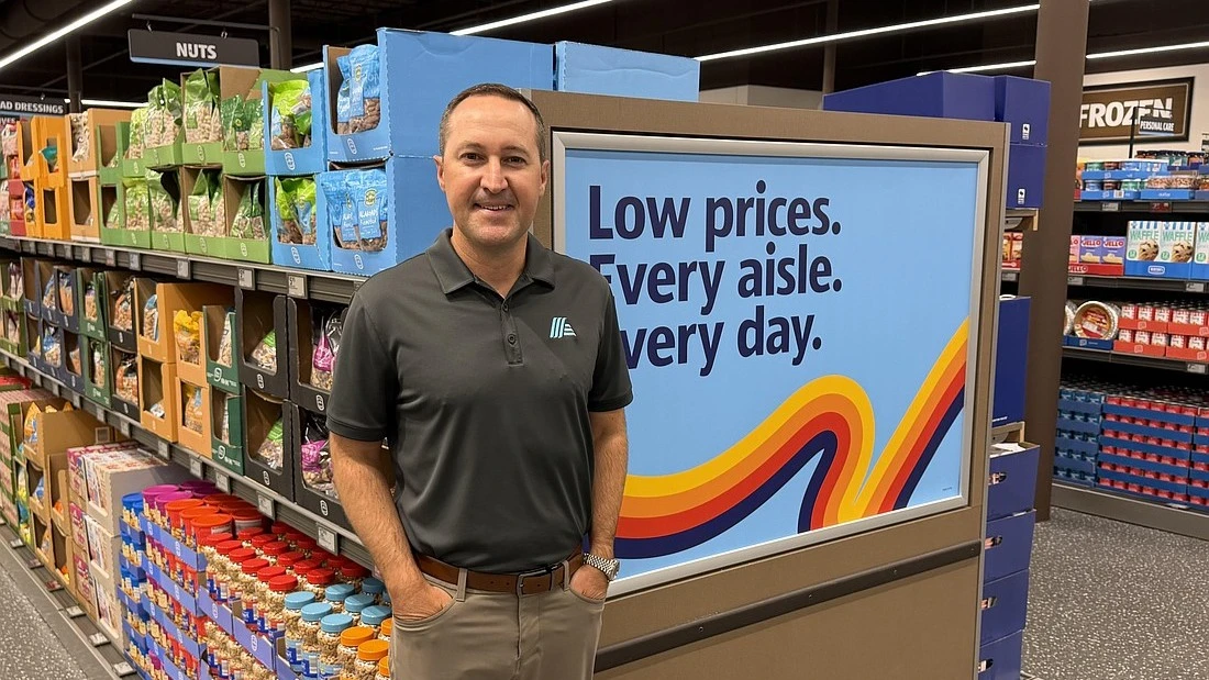 Aldi Regional Vice President JR Perry standing in front of a display case in the new Aldi store.