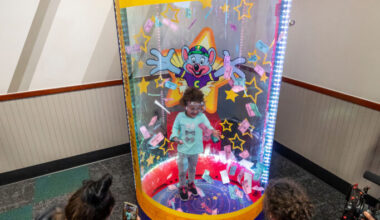 Young girl excitedly catching prize tickets inside the Ticket Blaster at Chuck E. Cheese.