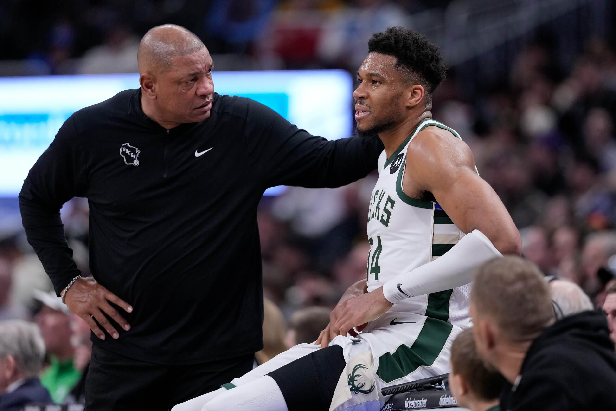 Bucks coach Doc Rivers checks on Giannis Antetokounmpo during a game, placing his hand on his shoulder.