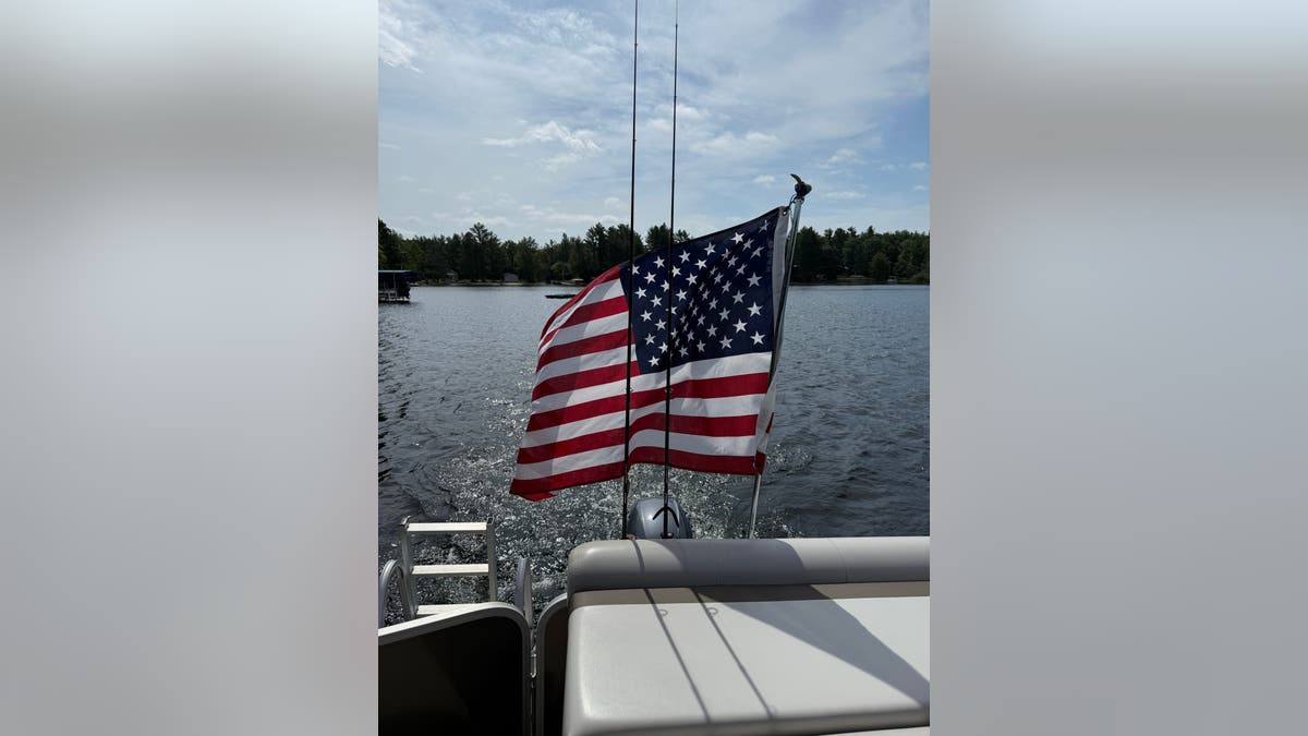 an American flag flies on the back of a boat on a lake
