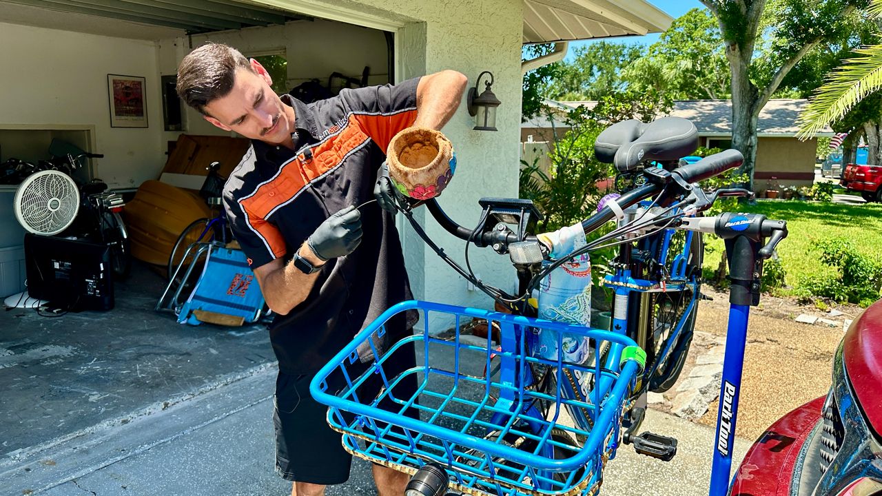 E-Mobilize Mobile Bike Service owner Jake McFadden repairs a customer's electric bicycle at her Palm Harbor home. (Spectrum News/Josh Rojas)
