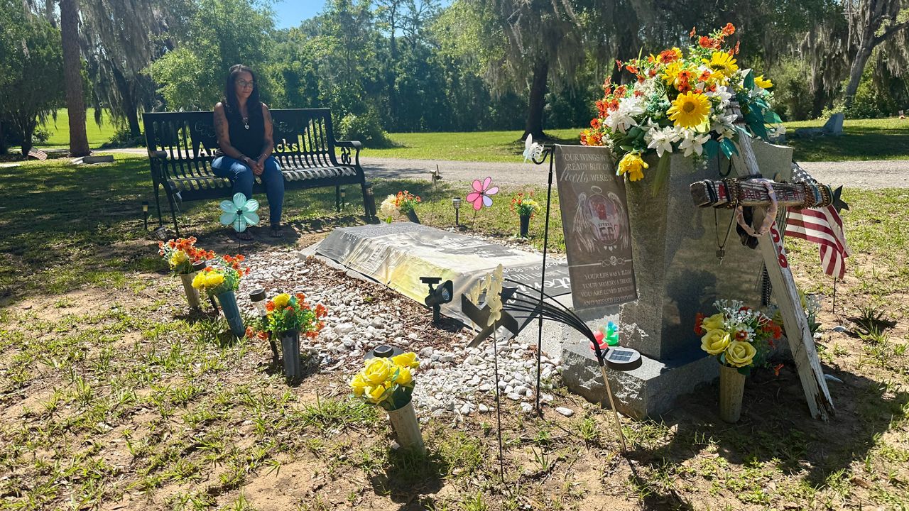 Lakesha Harrison, the mother of Antonio Hicks, sits at his gravesite. Antonio died from a heart issue in Citrus County a few years ago. (Spectrum News/Erin Murray)
