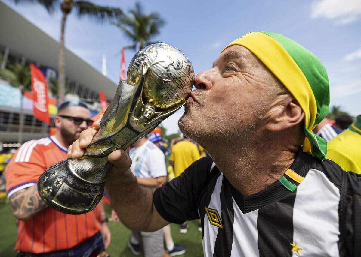 Brazil fan Eduardo Pascoal kisses a World Cup replica as he arrives to Hard Rock Stadium (Miami Stadium) before the start of his team's World Cup Group C soccer match against Scotland on Wednesday, June 24, 2026, in Miami Gardens, Fla.