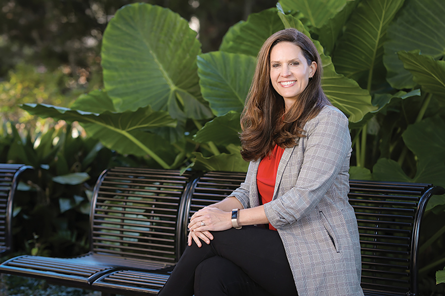 Photo of Marla Vickers sitting on a bench surrounded by plants.