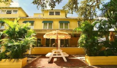 Exterior of a bed and breakfast with a yellow paint job and a picnic table with a yellow umbrella out front