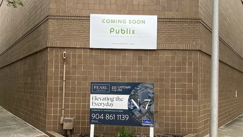 A sign on a building announces that Publix is coming soon.