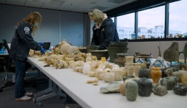 Two Homeland Security agents inspect thousands of artifacts, now evidence. (Spectrum News)