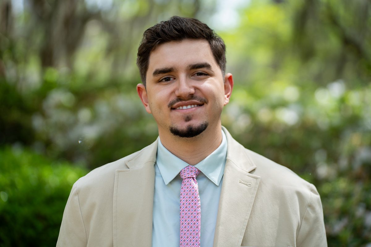 Sebastian Ruiz stands of front of greenery smiling.