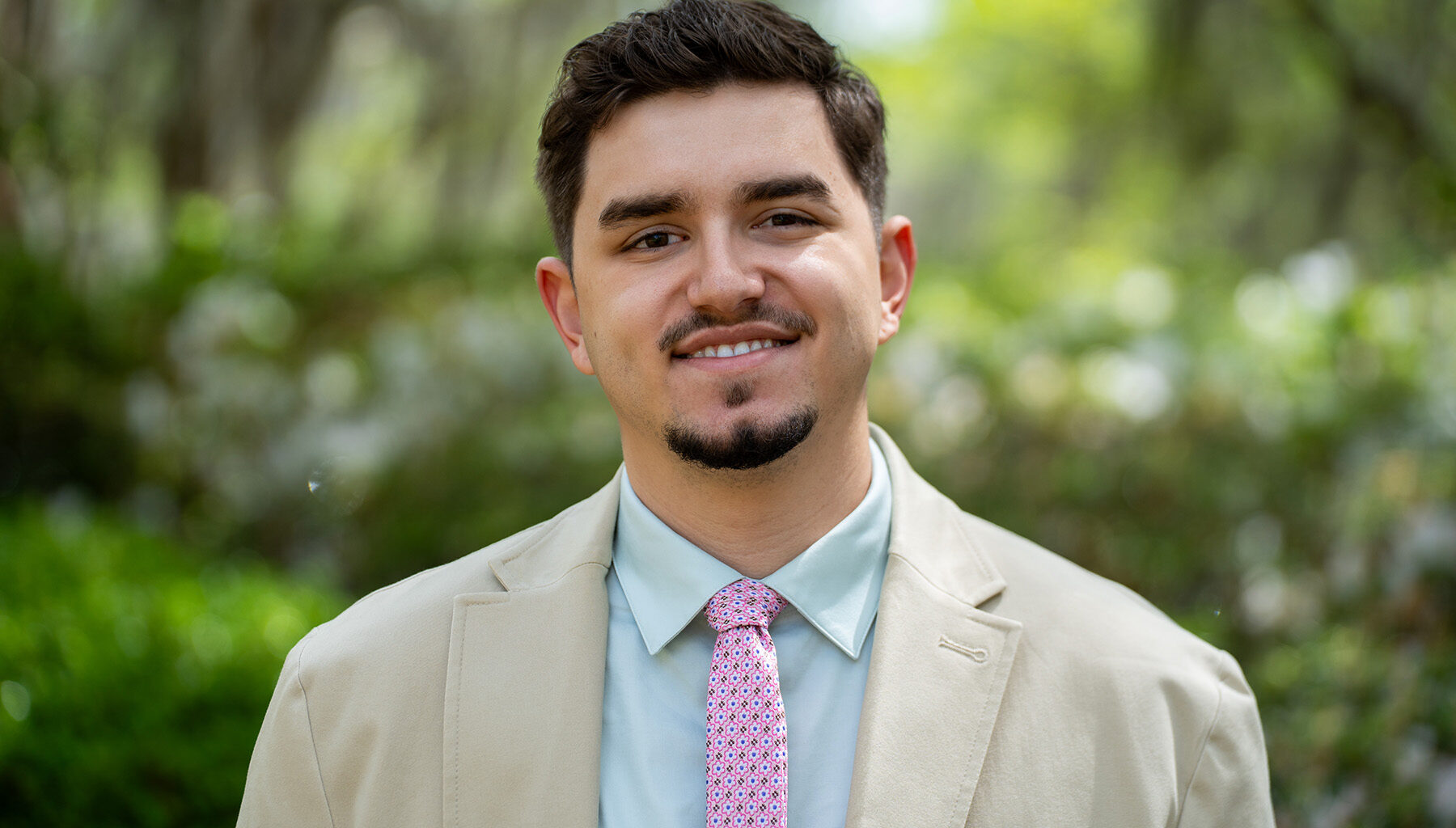 Sebastian Ruiz stands of front of greenery smiling.