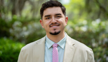Sebastian Ruiz stands of front of greenery smiling.