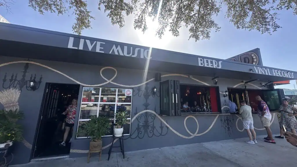 outside a bar/music venue. A window is open that allows the bar to serve guests sitting in high top chairs on the sidewalk