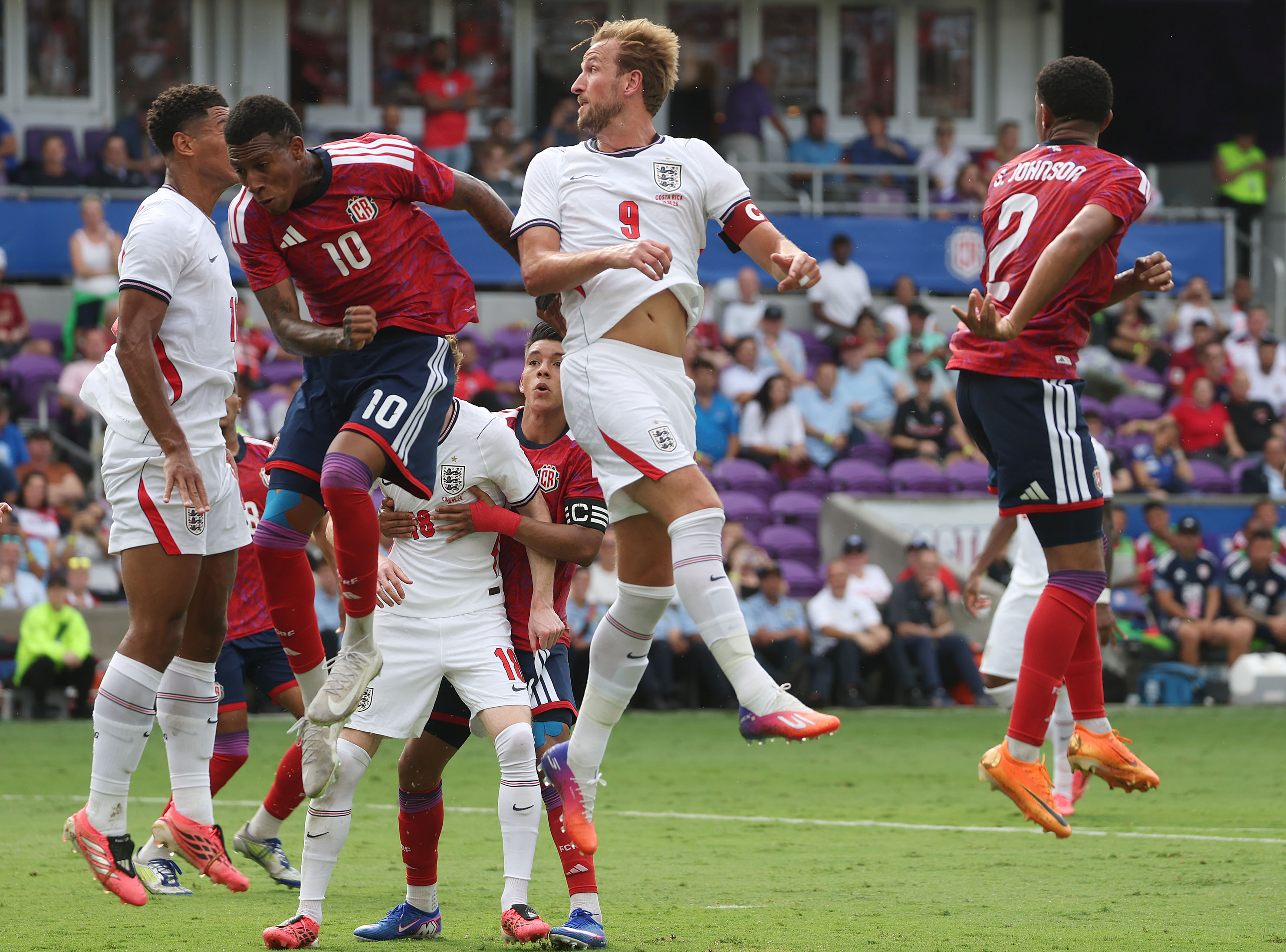 England star striker Harry Kane (9) leaps among other players...