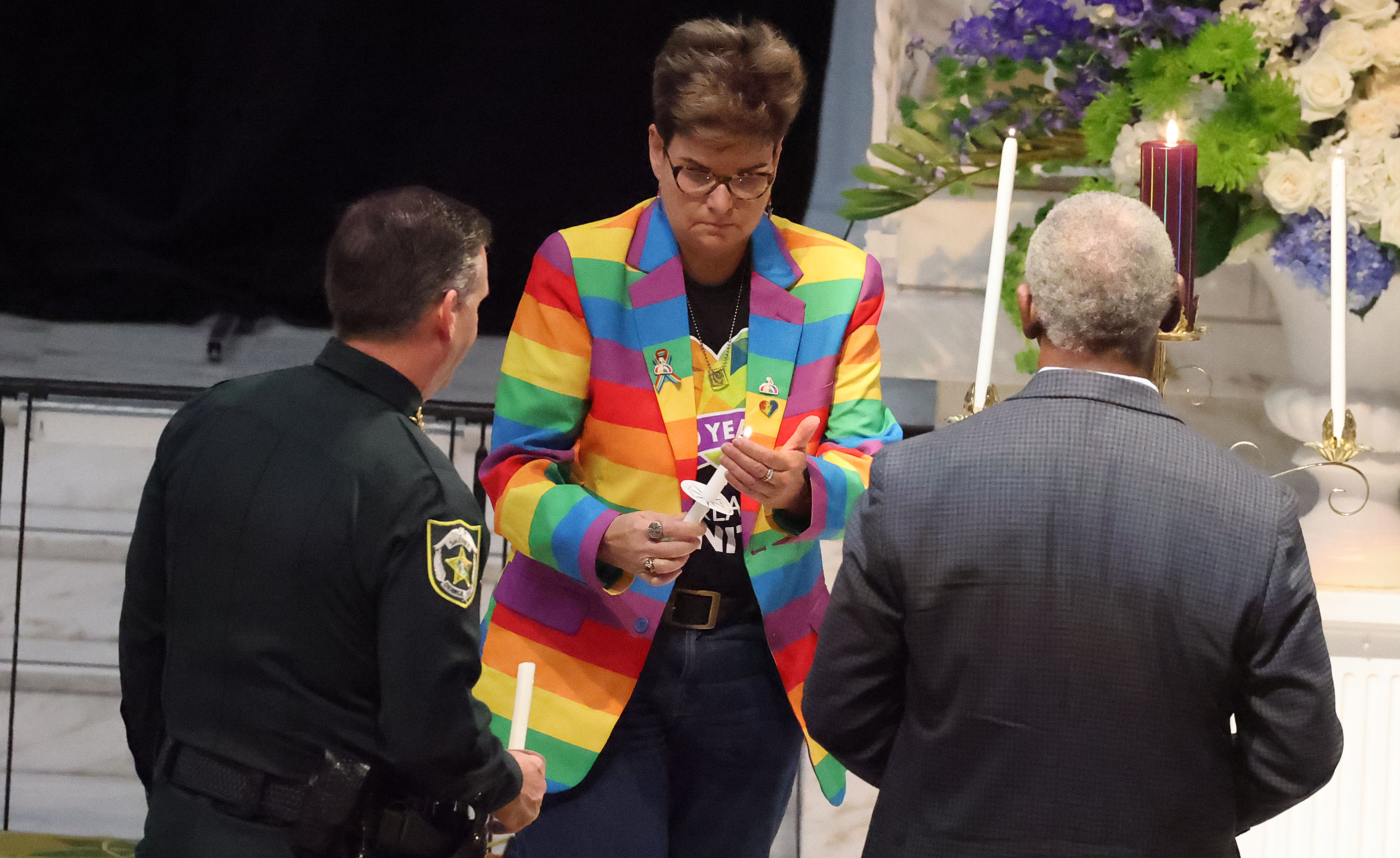 Orlando City Commissioner Patty Sheehan carries a lit candle uring...