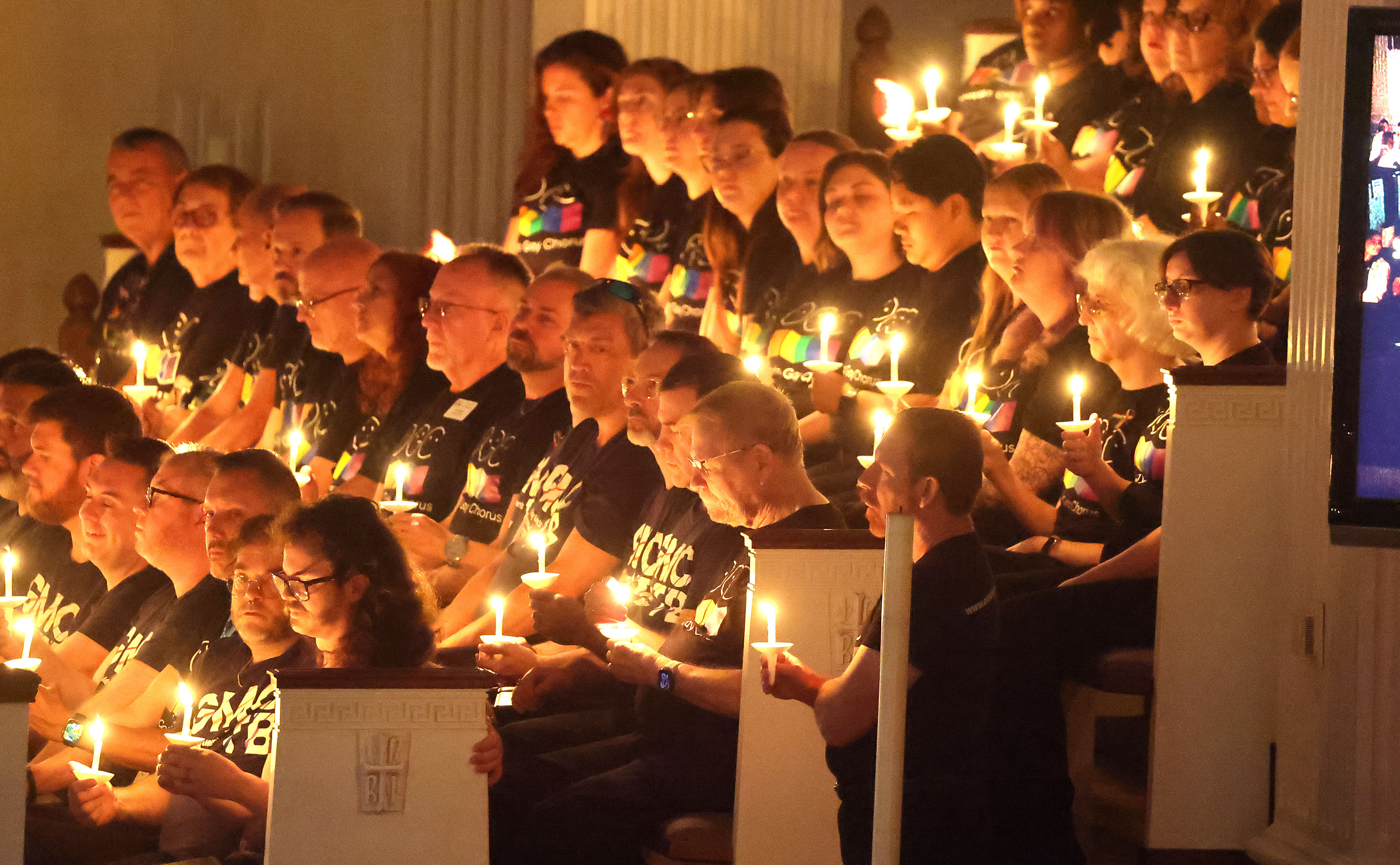 Members of the Orlando Gay Chorus hold burning candles during...