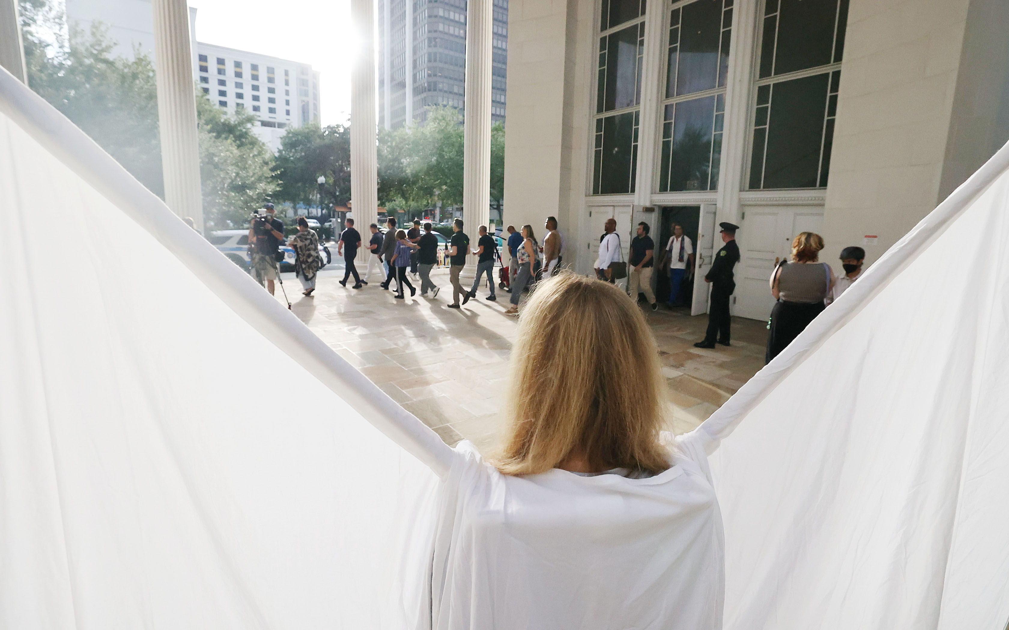 A woman wearing angel's wings stands as attendees file out...