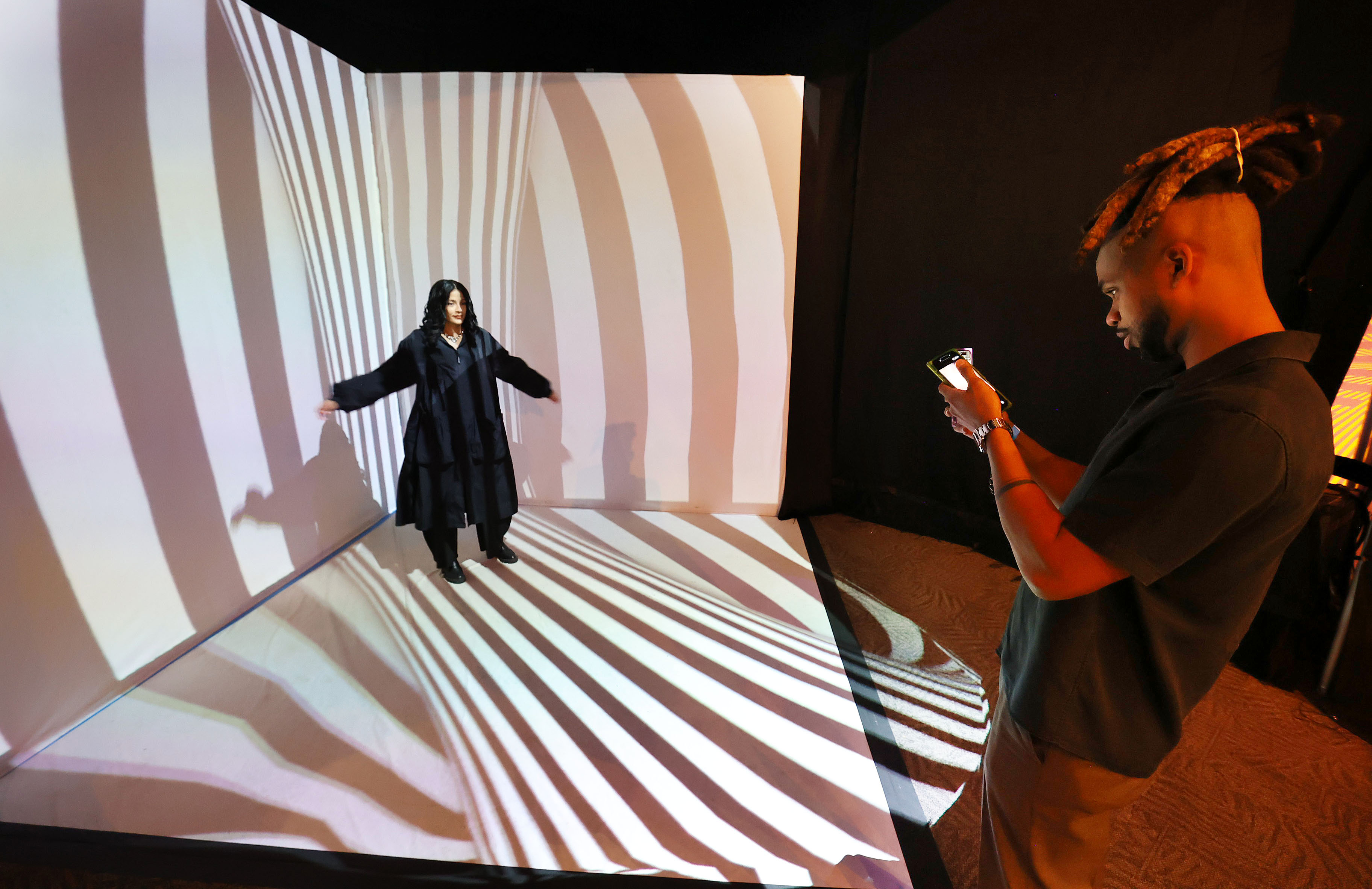 Guests take photos at an optical illusion exhibit during Orlando...