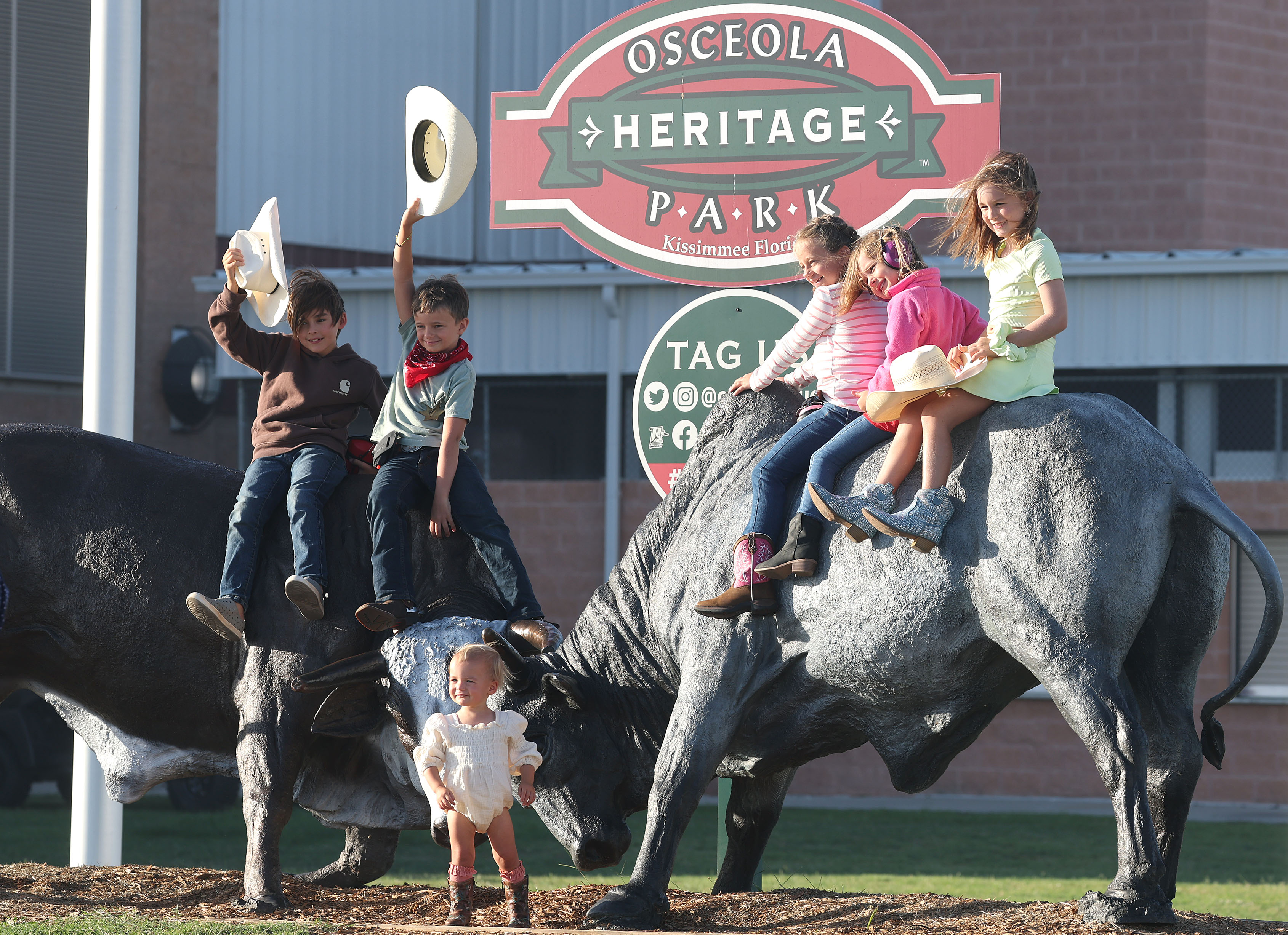 Kids pose on bull statues outside the arena before the...