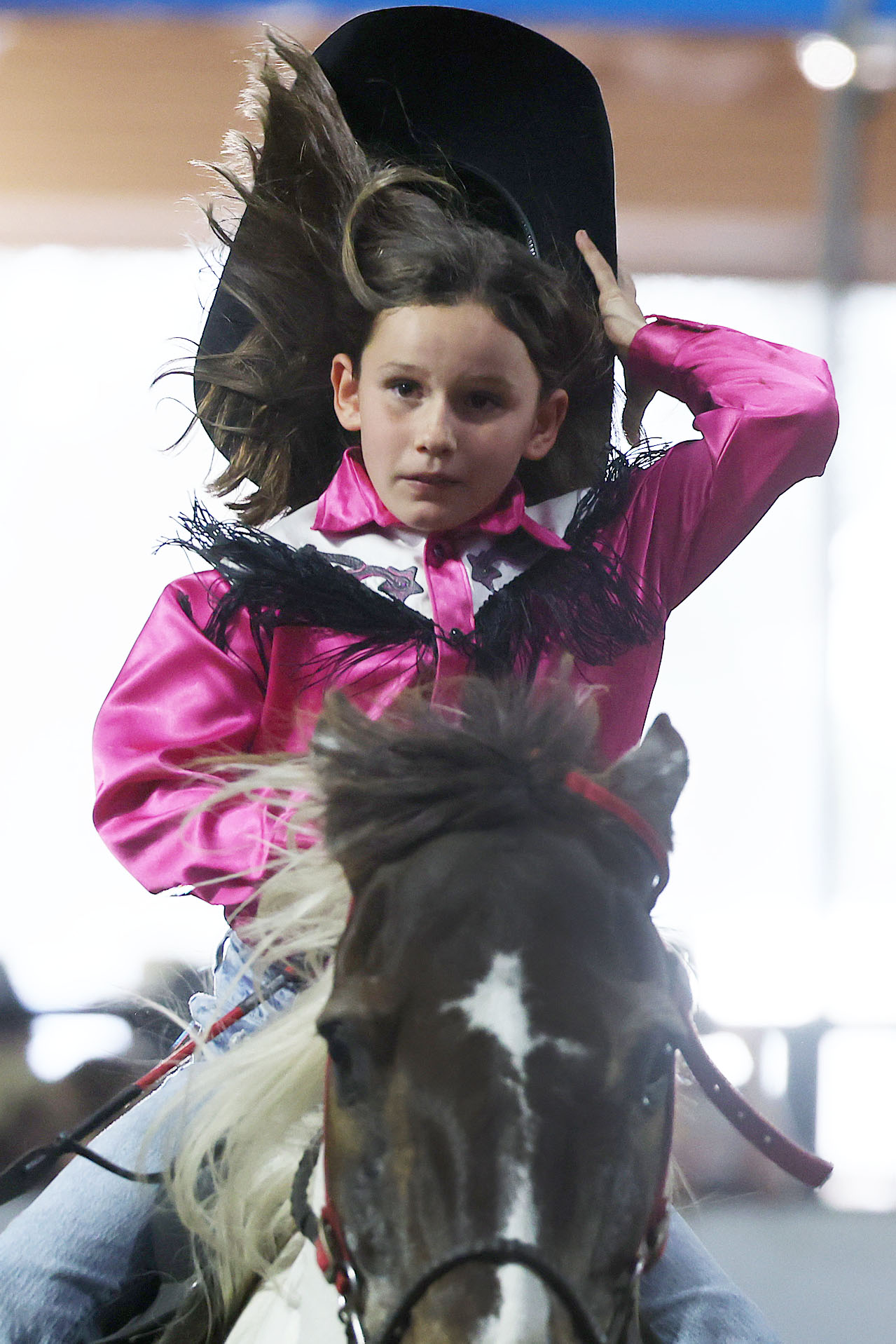 A cowgirl loses her hat as she rides during the...