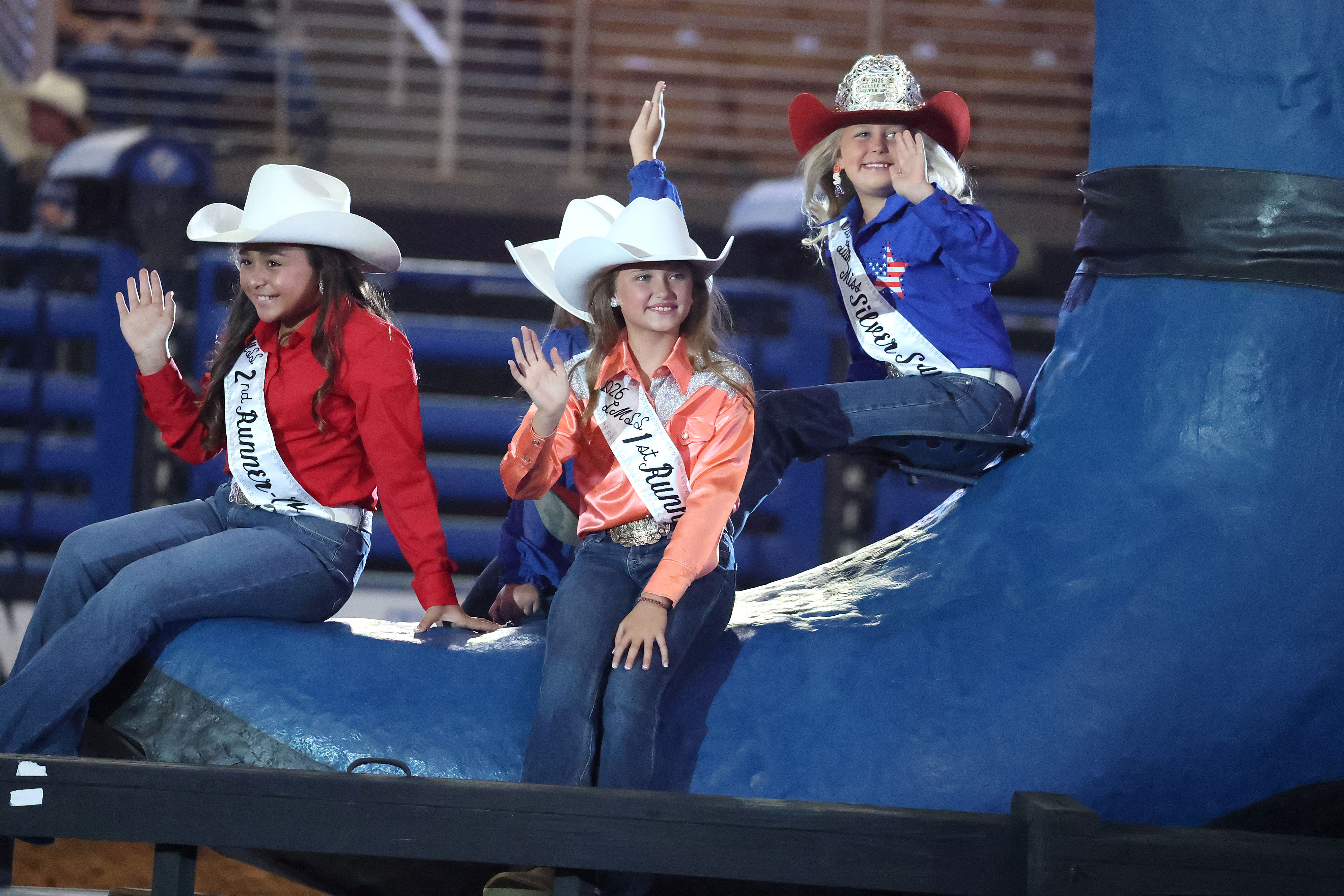 Young cowgirl rodeo queens wave to the crowd during the...