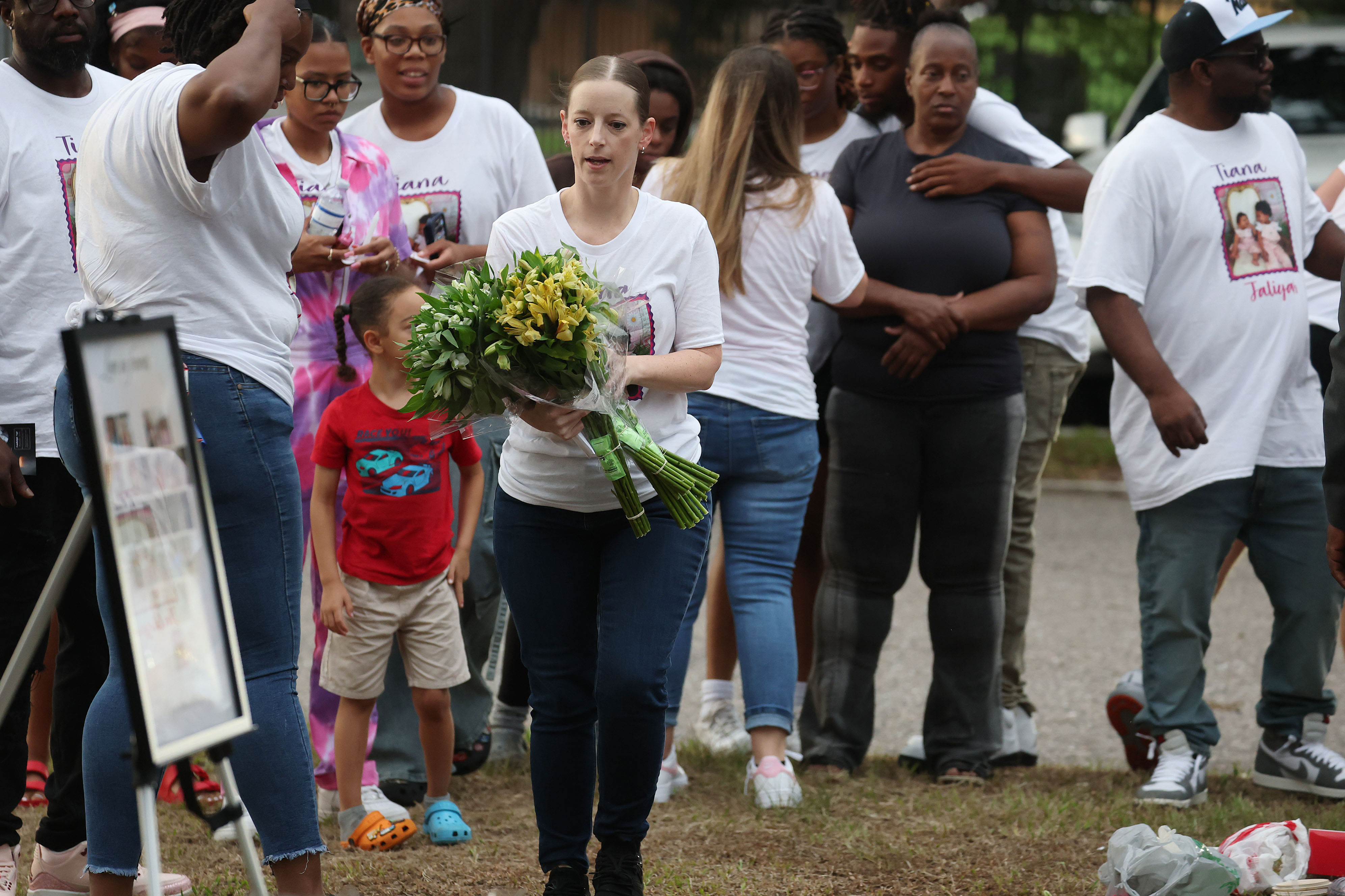 A mourner carries flowers during a community vigil for 2-year-old...