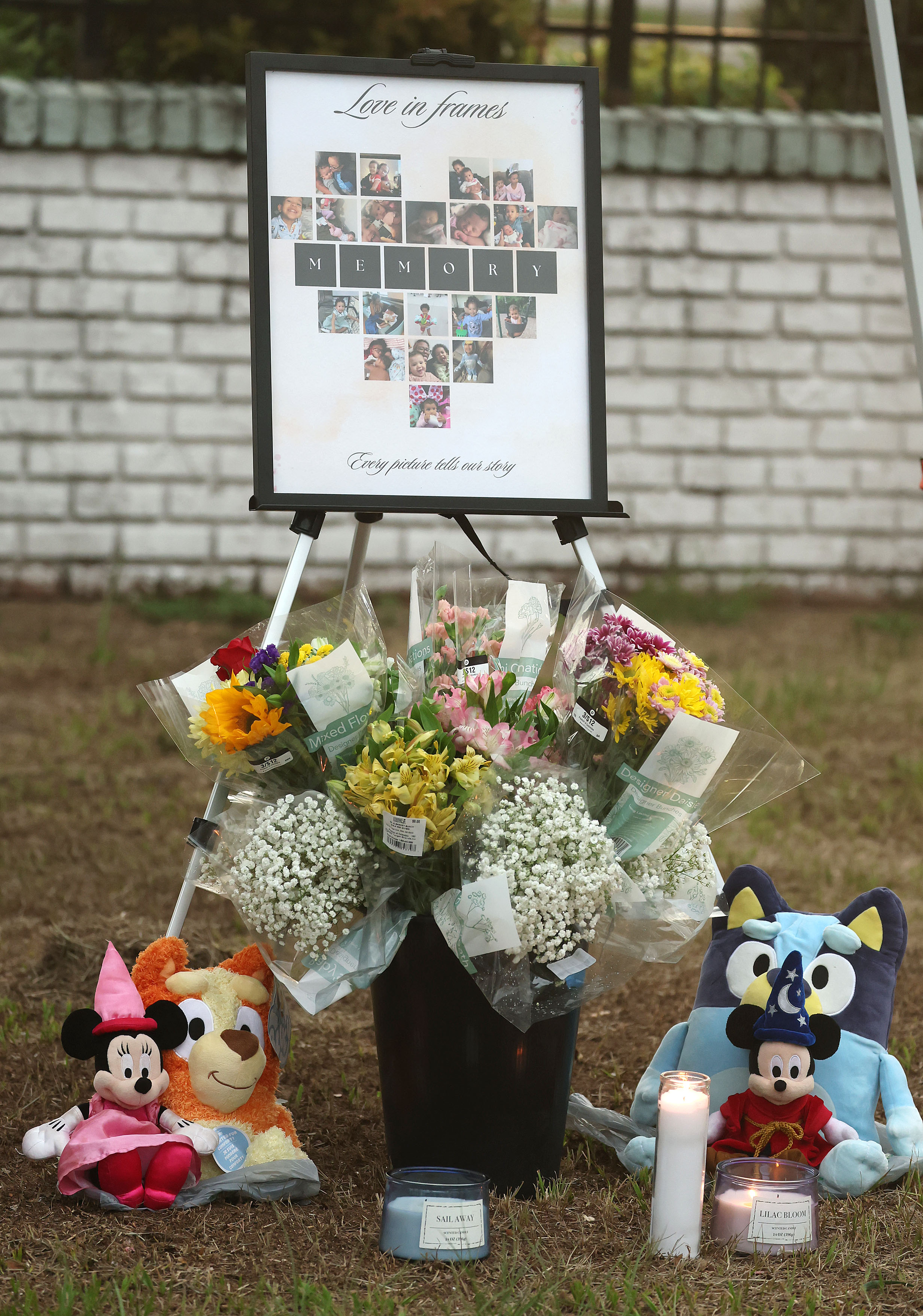 Photos, candles, flowers and stuffed animals are on display during...